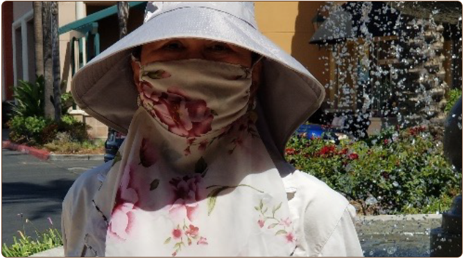 a woman in a white hat and a white shirt with a mask on her face
