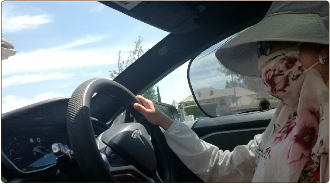 a woman driving a car in a white hat with a mask on her face